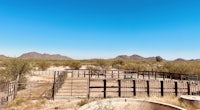 a ranch in the desert with a fenced in area